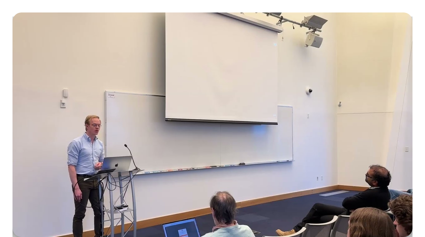 Andy Matuschak at a lectern with a laptop, a blank projection screen behind him, audience seated in the foreground
